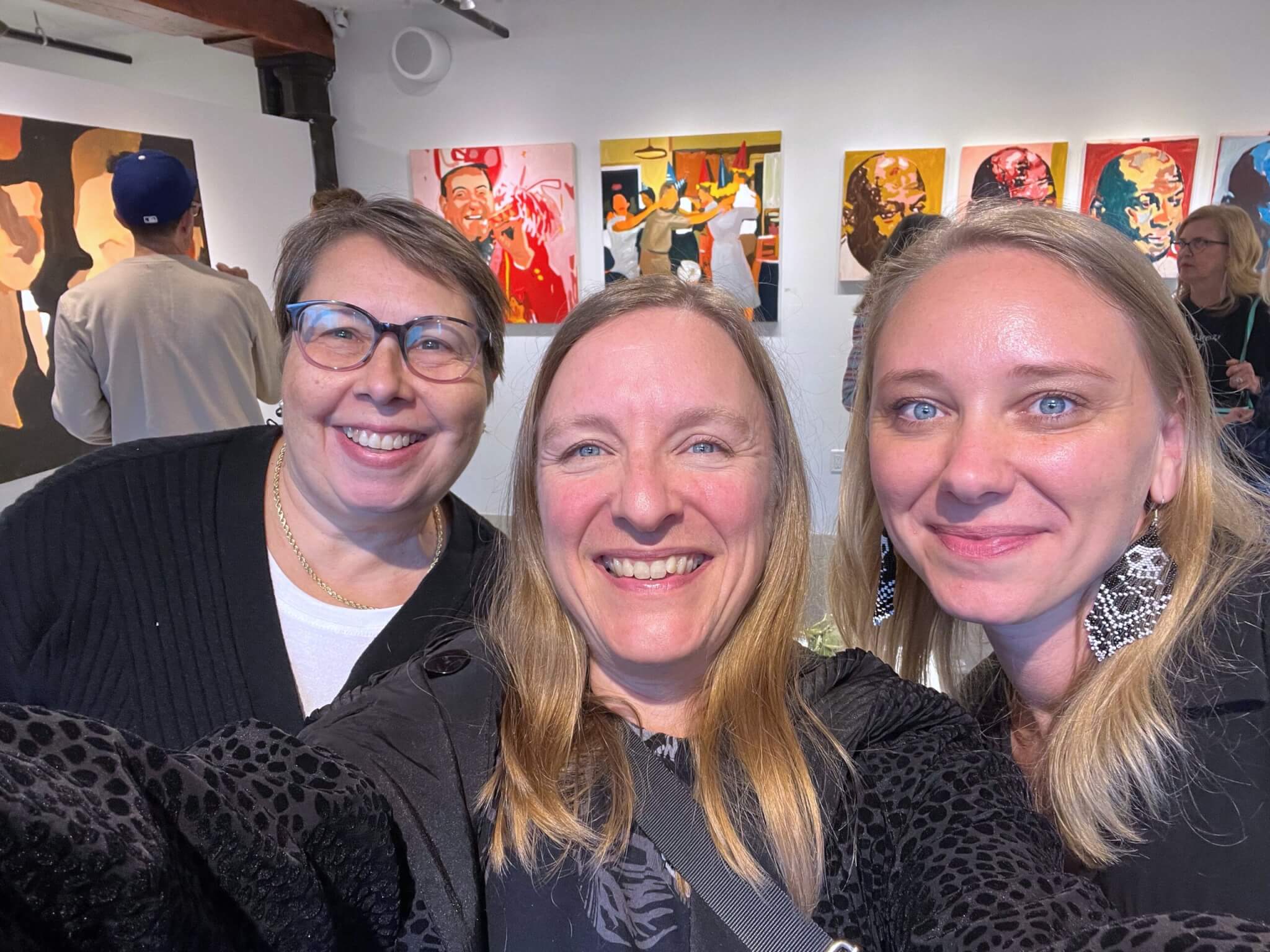A woman takes a selfie of herself and two others leaning in at either side of her.